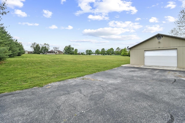 view of yard with an outbuilding, aphalt driveway, and a garage