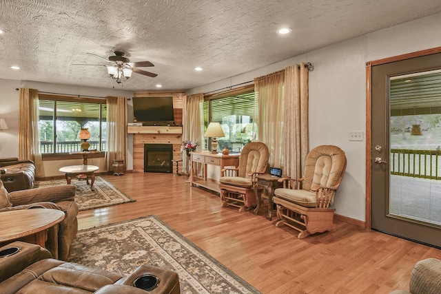 living room with a wealth of natural light, a ceiling fan, wood finished floors, and a fireplace