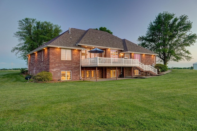 back house at dusk featuring a yard and a wooden deck