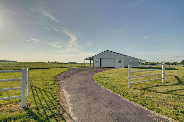 view of outbuilding with a rural view, a garage, and a yard