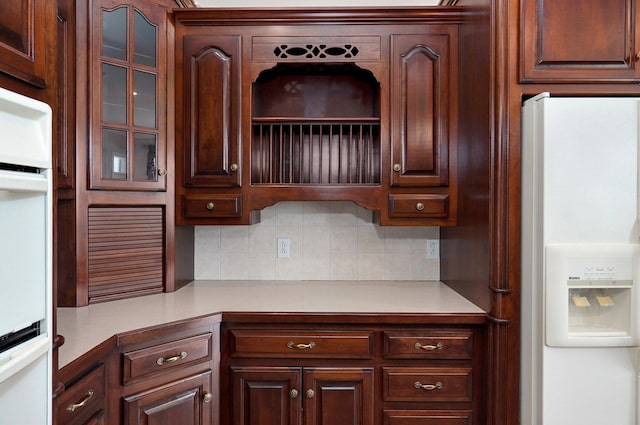 kitchen featuring dark brown cabinets, tasteful backsplash, and white appliances