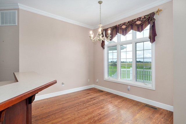 unfurnished dining area featuring ornamental molding, hardwood / wood-style floors, and an inviting chandelier