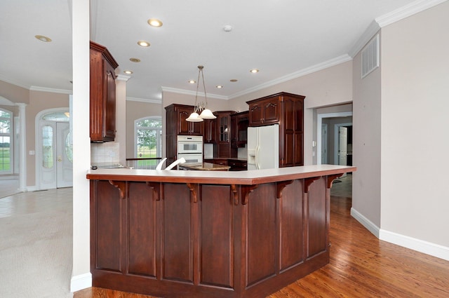 kitchen featuring hardwood / wood-style flooring, crown molding, kitchen peninsula, and white appliances