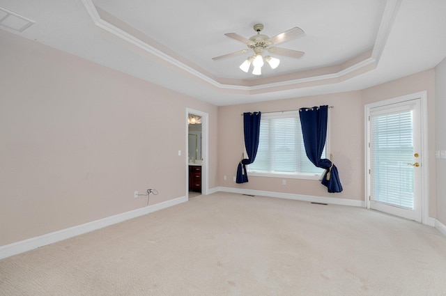 carpeted empty room with ceiling fan, a raised ceiling, crown molding, and a wealth of natural light