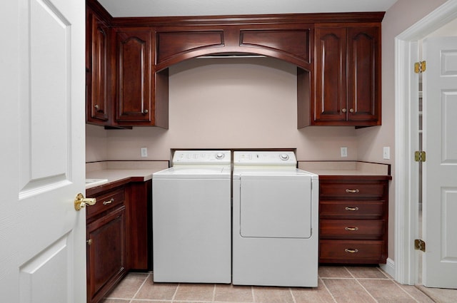 laundry area with washer and dryer, light tile patterned floors, and cabinets