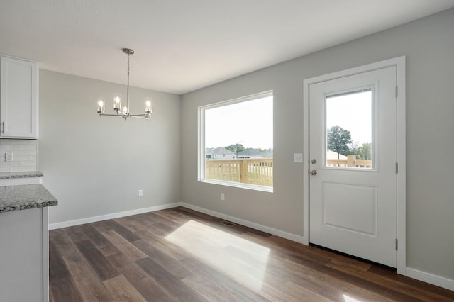 unfurnished dining area with a chandelier and dark hardwood / wood-style flooring