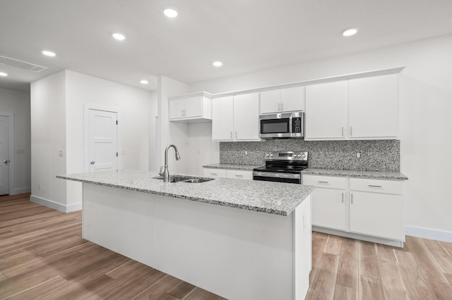 kitchen featuring white cabinets, appliances with stainless steel finishes, sink, and a kitchen island with sink