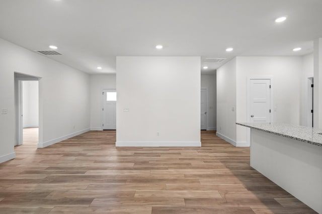 unfurnished living room with light wood-type flooring, baseboards, visible vents, and recessed lighting