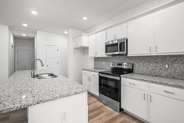 kitchen featuring tasteful backsplash, wood finished floors, a sink, white cabinetry, and appliances with stainless steel finishes