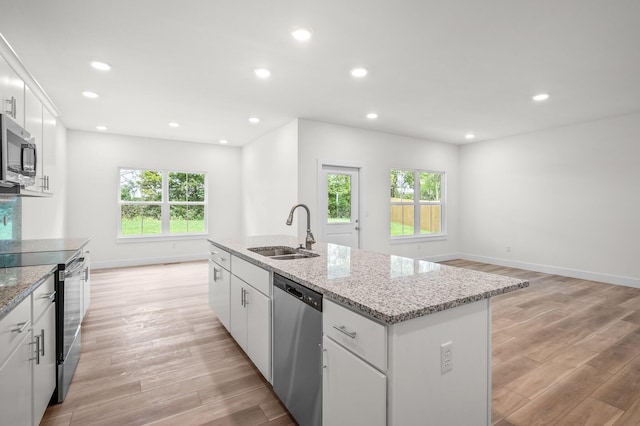 kitchen with appliances with stainless steel finishes, a center island with sink, white cabinetry, and sink