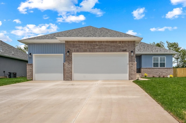 view of front facade featuring central AC, a front yard, and a garage