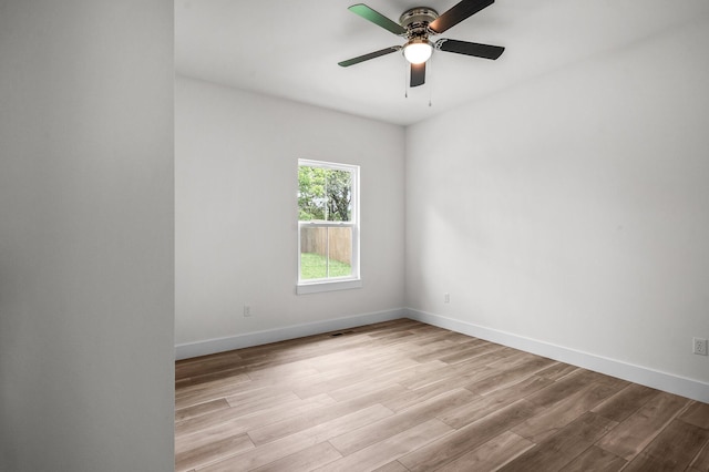 empty room featuring light wood finished floors, baseboards, and ceiling fan