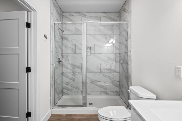 bathroom featuring wood-type flooring, vanity, a shower with shower door, and toilet