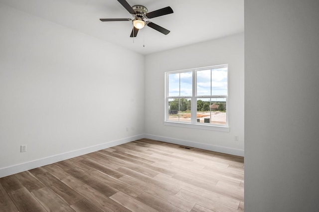 spare room with light wood-style flooring, visible vents, a ceiling fan, and baseboards