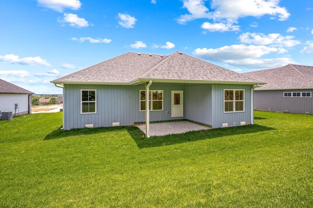 rear view of property featuring roof with shingles, a yard, and a patio