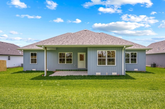 back of house with central air condition unit, roof with shingles, a patio, and a lawn