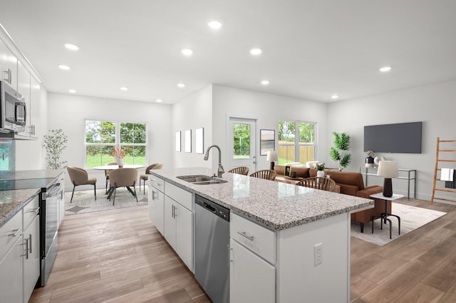 kitchen featuring light hardwood / wood-style flooring, a center island with sink, sink, stainless steel appliances, and white cabinetry