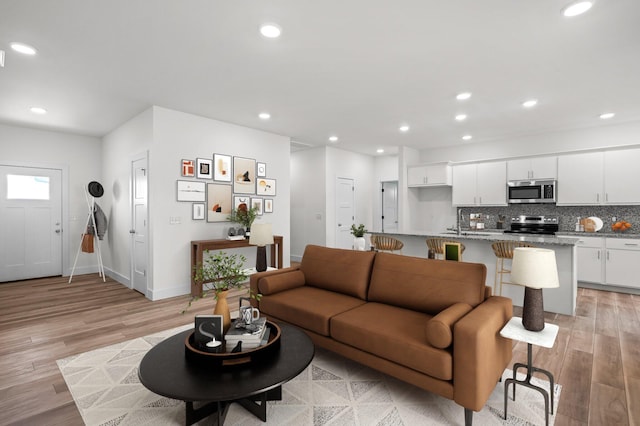 living room featuring light wood-type flooring, baseboards, and recessed lighting