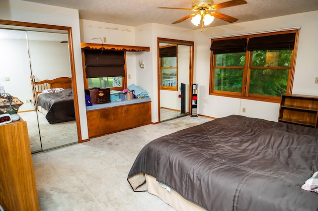 carpeted bedroom featuring ceiling fan, two closets, and a textured ceiling