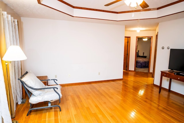 sitting room with ceiling fan, crown molding, and hardwood / wood-style floors