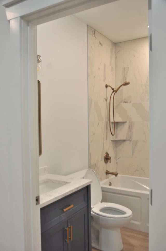 full bathroom with hardwood / wood-style flooring, vanity, toilet, and tiled shower / bath combo