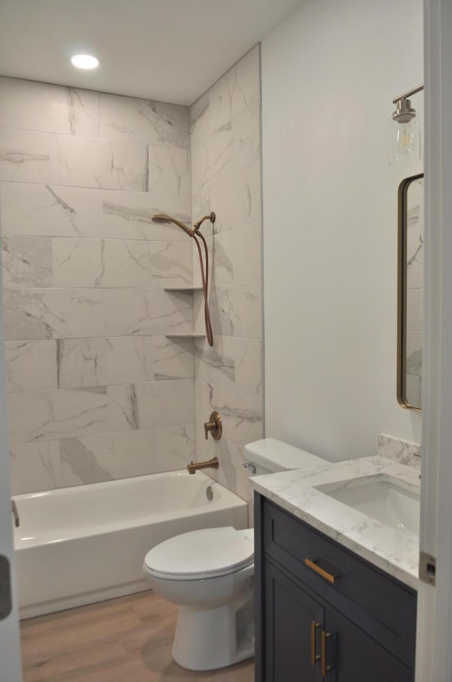 full bathroom with tiled shower / bath combo, vanity, wood-type flooring, and toilet