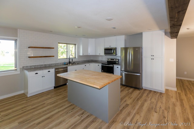 kitchen featuring a kitchen island, white cabinetry, stainless steel appliances, and light wood-type flooring