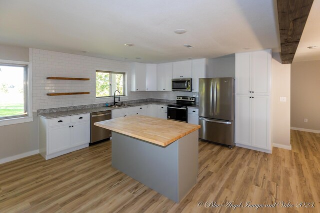 kitchen with stainless steel appliances, a sink, light wood-style floors, baseboards, and wood counters