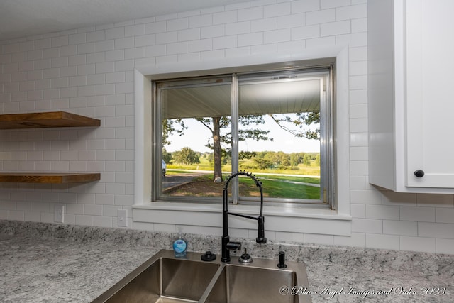 room details with decorative backsplash, open shelves, a sink, and light stone countertops
