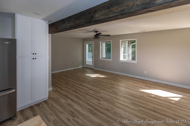 unfurnished living room with beamed ceiling, wood finished floors, baseboards, and a ceiling fan