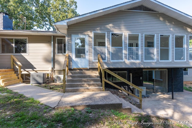 rear view of house with a chimney, entry steps, cooling unit, and a patio