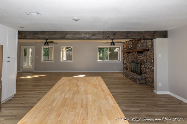 unfurnished living room with a fireplace, ceiling fan, dark hardwood / wood-style flooring, and a textured ceiling