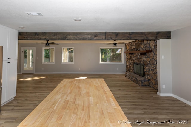unfurnished living room featuring beamed ceiling, wood finished floors, visible vents, and a ceiling fan