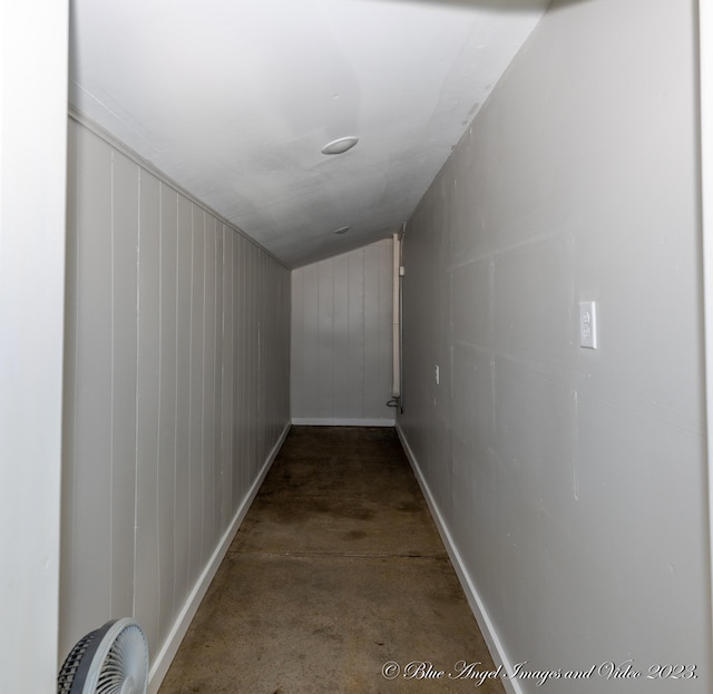 hallway with concrete flooring and wooden walls