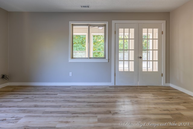 doorway to outside featuring light wood-type flooring, plenty of natural light, french doors, and a textured ceiling