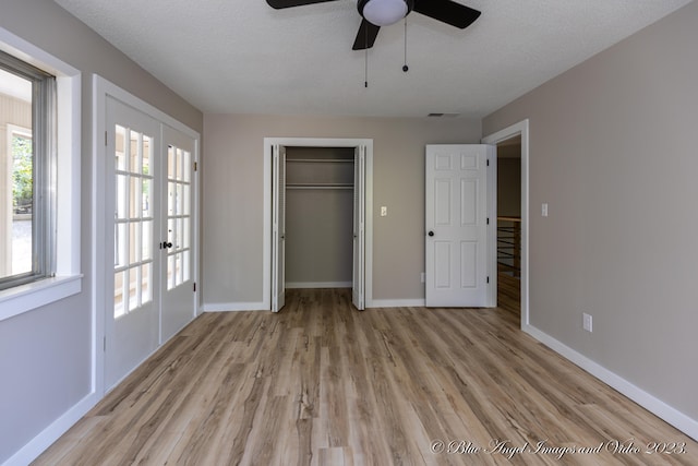 unfurnished bedroom with light wood-type flooring, ceiling fan, a closet, french doors, and a textured ceiling