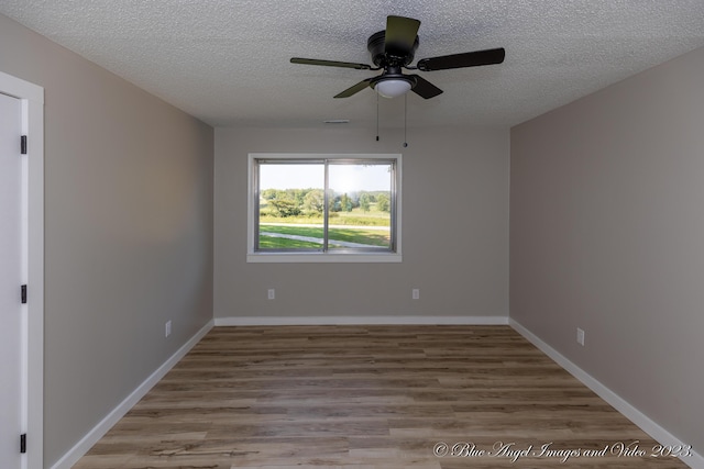 empty room with baseboards, a ceiling fan, wood finished floors, and a textured ceiling