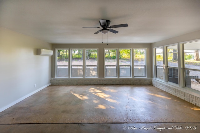unfurnished sunroom with baseboards, an AC wall unit, and concrete flooring