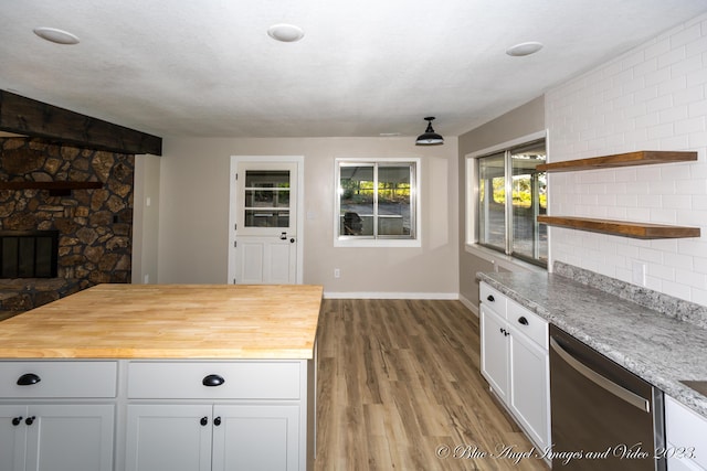 kitchen featuring wood counters, stainless steel dishwasher, open shelves, and a stone fireplace