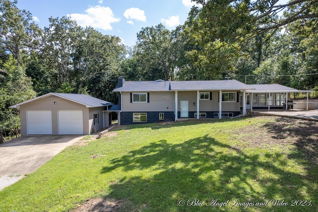 raised ranch with a detached garage, a chimney, and a front yard