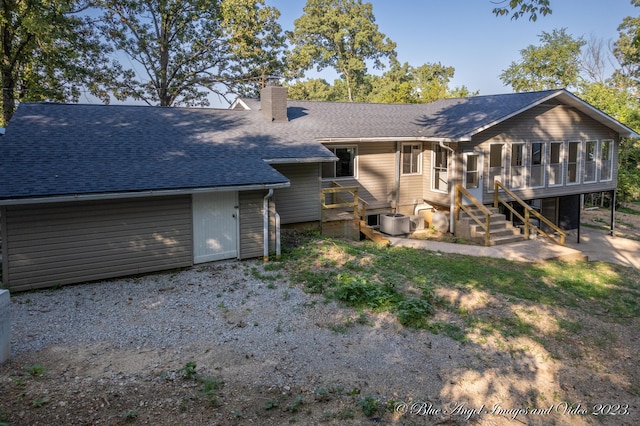 view of front of property featuring a chimney, a sunroom, roof with shingles, and central AC unit