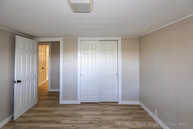 unfurnished bedroom with a closet, hardwood / wood-style floors, and ornamental molding