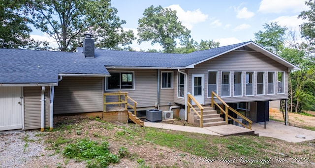 rear view of property featuring a patio, a shingled roof, a chimney, and central AC unit