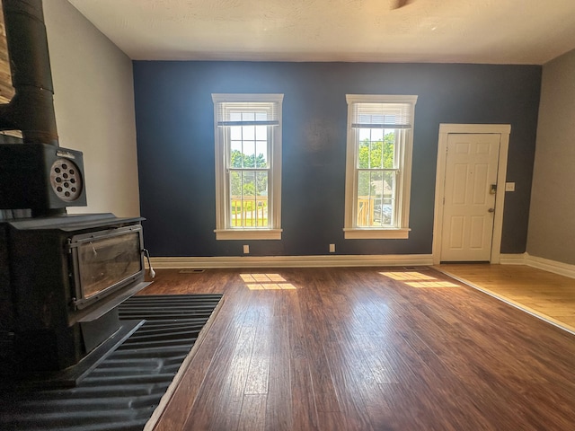 unfurnished living room featuring dark hardwood / wood-style flooring and a wood stove