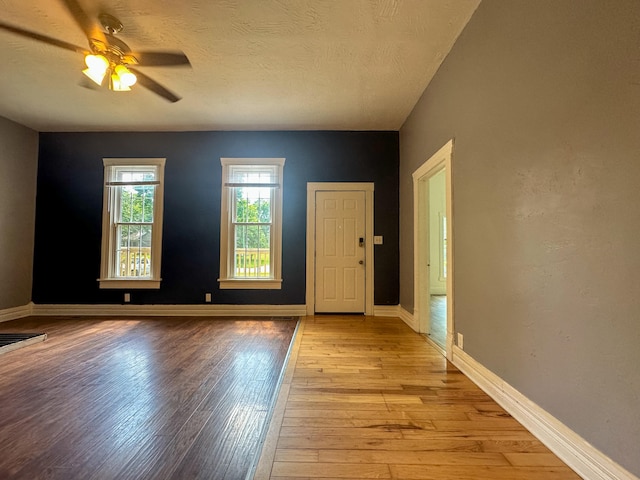 unfurnished room with a textured ceiling, ceiling fan, and light hardwood / wood-style flooring