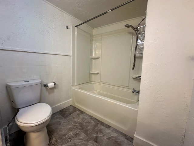 bathroom with bathing tub / shower combination, tile walls, tile patterned floors, and toilet