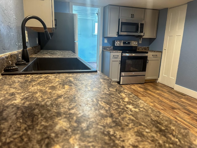 kitchen with wood-type flooring, stainless steel appliances, sink, and gray cabinetry