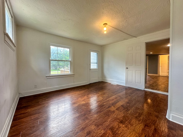 spare room featuring a textured ceiling and dark wood-type flooring