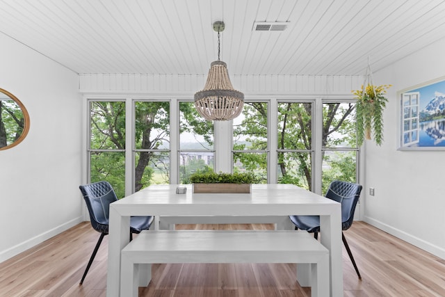 dining room with light wood-type flooring, a wealth of natural light, and an inviting chandelier