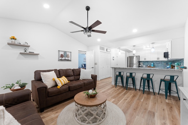 living room featuring light hardwood / wood-style floors, vaulted ceiling, and ceiling fan